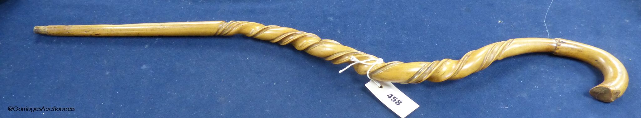 A carved wood walking stick in the style of a narwal tusk